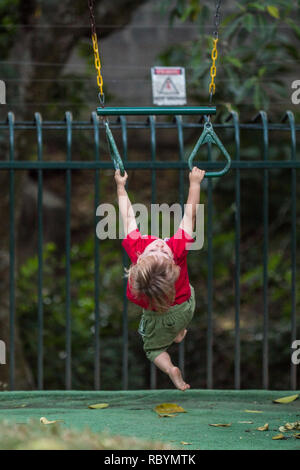 Ein Foto von einem starken toddler Training auf Pull up Fitnessstudio Ringe Stockfoto