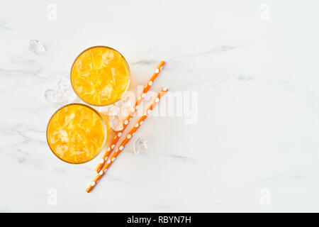 Frische Orange, Mango oder Zitronensaft im hohen Glas mit Eis und Strohhalme auf weißem Hintergrund. Im Sommer trinken. Ansicht von oben. Kopieren Sie Platz für Text. Stockfoto