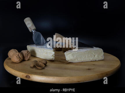 Holz- drehbare Platte mit französischem Käse genannt Brie mit einem Messer und Walnüsse und Mandeln Stockfoto