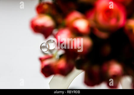 Foto Hochzeit Ringe durch ein Bouquet von roten Blumen Stockfoto