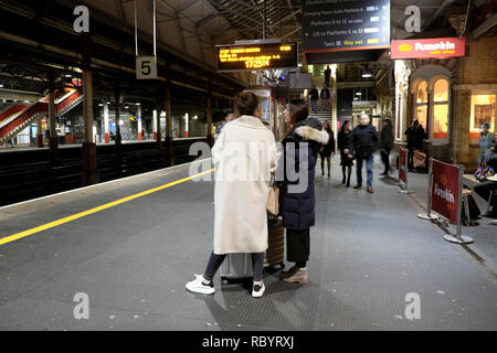 Hintere Rückseite der Passagiere Frau auf der Plattform in Crewe Bahnhof warten auf eine Jungfrau Zug nach London UK KATHY DEWITT Stockfoto