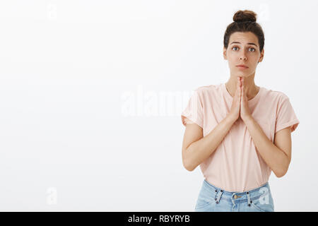 Mädchen, die wie Engel als Betteln um die Gunst oder Hilfe Hände halten in beten und nette aufrichtige Ausdruck, wollen Freund Geld leihen Antizipation mersy stehend gegen grauer Hintergrund Stockfoto