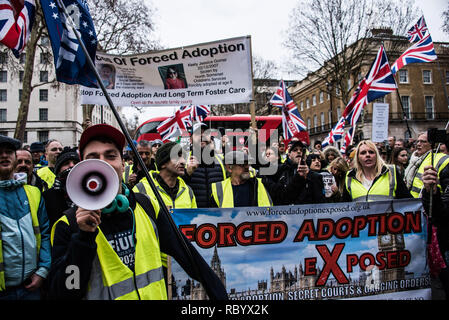 Ein rechter Demonstrant gesehen Parolen auf ein Megaphon vor den Demonstranten halten Transparente und Fahnen während des Protestes. Tausenden sammelten in London für die "Volksversammlung gegen Sparpolitik" durch Proteste der französischen 'gelbe Weste' aufmerksam zu Sparmaßnahmen, die die Armen hart getroffen haben, inspiriert. Stockfoto