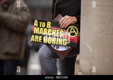 Eine Demonstrantin hält ein Plakat gesehen, das liest, "A nach B Märsche langweilig' Während des Protestes. Tausenden sammelten in London für die "Volksversammlung gegen Sparpolitik" durch Proteste der französischen 'gelbe Weste' aufmerksam zu Sparmaßnahmen, die die Armen hart getroffen haben, inspiriert. Stockfoto