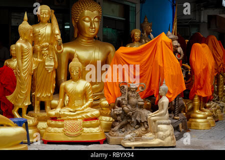 Buddha Statuen an ein Geschäft mit religiösen Artefakten in Bamrung Muang Rd., Bangkok, Thailand, einige mit orange Tuch bedeckt in der Nacht 'sleep' Stockfoto