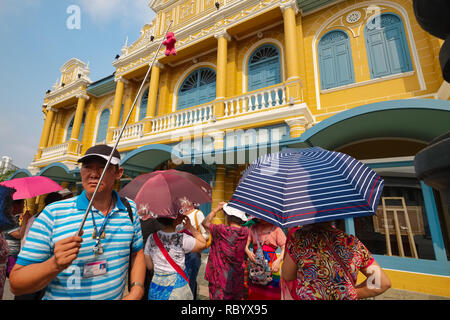 Eine chinesische Reiseleiter vor einem Gebäude im Kolonialstil in Bangkok, Thailand, Hirten seiner Chinesischen Reisegruppe von Wat Phra Kaew zu Tha Chang Pier Stockfoto