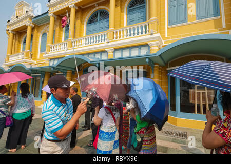 Eine chinesische Reiseleiter vor einem Gebäude im Kolonialstil in Bangkok, Thailand, Hirten seiner Chinesischen Reisegruppe von Wat Phra Kaew zu Tha Chang Pier Stockfoto