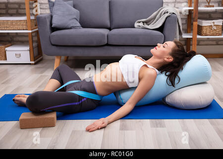 Entspannt junge Frau liegend auf Fitness Matte, Übung mit Yoga Gurt Stockfoto