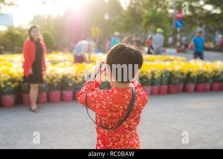 Kleiner Junge macht ein Foto von seiner Mutter auf der Digitalkamera bei Tet Blumenmarkt Stockfoto