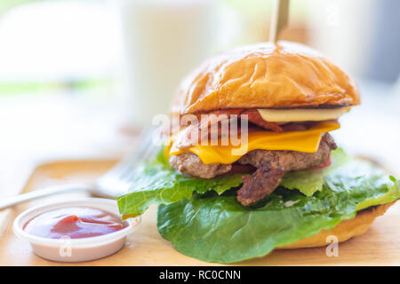 Hausgemachte stil Hamburger mit mehreren Schichten von Rindfleisch, Käse und Speck mit Ketchup Soße auf der Seite Stockfoto