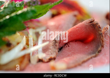 Roastbeef mit Bratkartoffeln, dekoriert mit essbaren Sky und Kräutern | Roastbeef mit Braten oder Bratkartoffeln Stockfoto