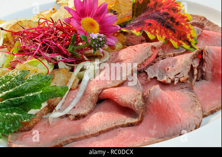 Roastbeef mit Bratkartoffeln, dekoriert mit essbaren Sky und Kräutern | Roastbeef mit Braten oder Bratkartoffeln Stockfoto