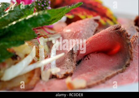 Roastbeef mit Bratkartoffeln, dekoriert mit essbaren Sky und Kräutern | Roastbeef mit Braten oder Bratkartoffeln Stockfoto