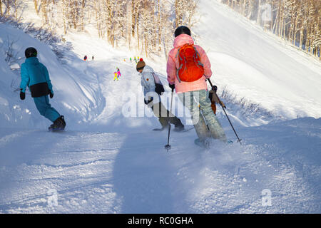 Skifahrer und Snowboarder reiten auf einer Skipiste in Sotschi Mountain Resort auf verschneiten Winter Berg Hintergrund malerische Aussicht Stockfoto