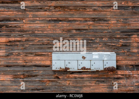 Alte hölzerne Planke Wand mit gebrochenen Farben und Mailboxen. Nahaufnahme. Stockfoto