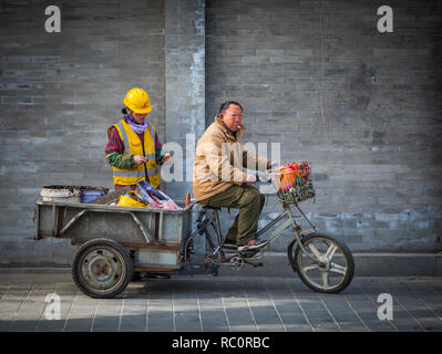 Mann, der Arbeit Material auf einem Dreirad im Zentrum von Peking, China Stockfoto