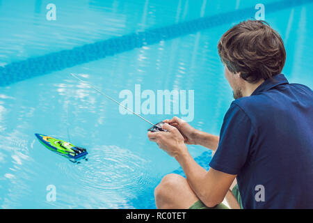 Mann spielt mit einem ferngesteuerten Boot im Pool. Stockfoto