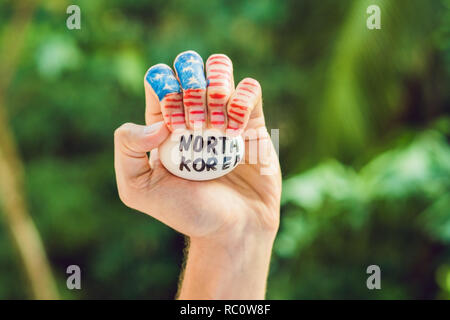 Die USA hand drückt auf die Nordkoreanischen Ei. Konflikt zwischen den Vereinigten Staaten und Nordkorea. Stockfoto