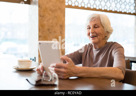 Fröhlich aufgeregt ältere Frau genießen Lesung im Cafe Stockfoto