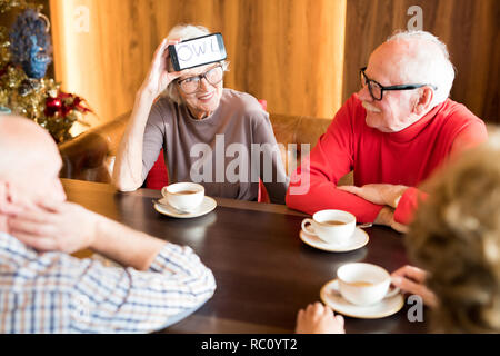 Lächelnde ältere Dame spielen Word - Ratespiel mit besten Freunden Stockfoto