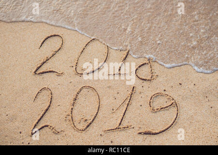 Neues Jahr 2019 kommt Konzept - Inschrift 2018 und 2019 auf einem Strand Sand, die Welle ist fast für die Ziffern 2018. Stockfoto