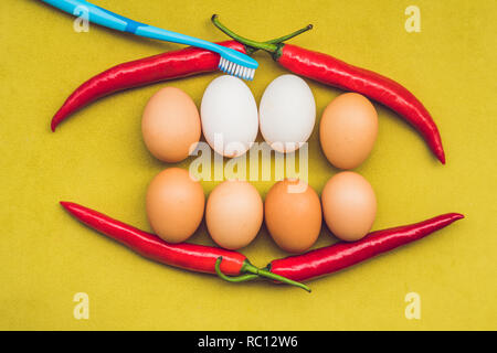 Eier und rote Paprika in Form eines Mundes mit Zähnen. Weiße Eier sind Gebleichte Zähne. Gelbe Eier - vor dem Bleichen. Zähne, die vor und nach dem Stockfoto