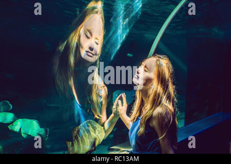 Junge Frau von Fisch in einem Tunnel Aquarium suchen Stockfoto