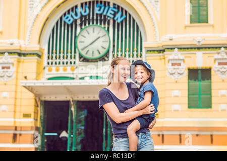 Mutter und Sohn auf Hintergrund Saigon Central Post Office auf blauen Himmel Hintergrund in Ho Chi Minh, Vietnam. Beschriftung in Vietnamesisch-Post Stockfoto