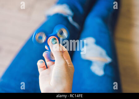 Mädchen Teenager in Löchrige jeans hält in der Hand und spielt mit Spinner Stockfoto