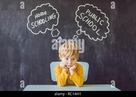 Homeschooling vs Öffentlichen Schulen - der Junge sitzt am Tisch und wählt zwischen Schulende und öffentliche Schule - durch Lehrer vs erzogen werden, lernen und zu Hause mit den Eltern Studie Stockfoto