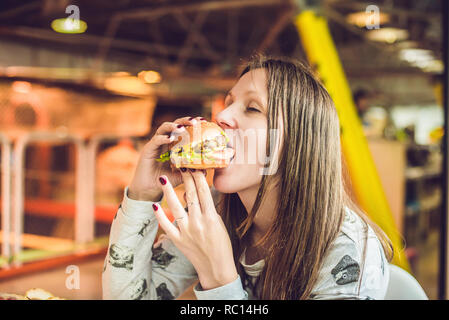 Junge Frau essen Hamburger Frau Essen der Trödelnahrung, fetthaltige Lebensmittel Hamburger Stockfoto