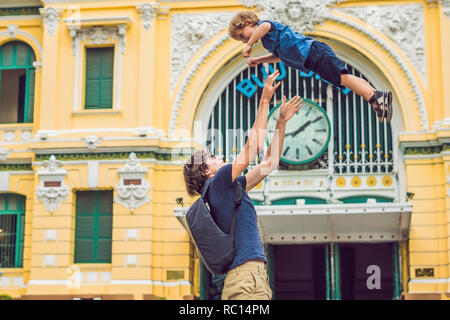 Vater und Sohn auf Hintergrund Saigon Central Post Office auf blauen Himmel Hintergrund in Ho Chi Minh, Vietnam. Stahlkonstruktion des gotischen Gebäude wurde von Gustave Eiffel entworfen wurde. Stockfoto