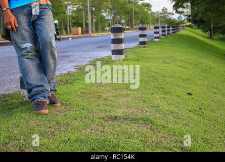 Mann Bein stand neben der Straße mit Sonnenuntergang. Stockfoto