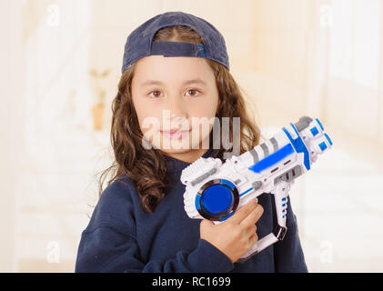 Glückliche kleine Mädchen, dass eine Waffe in der Hand und tragen junge Kleidung Stockfoto