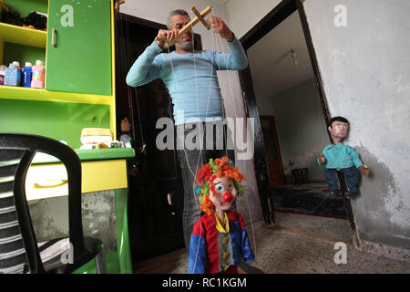 Januar 13, 2019 - Gaza, Gazastreifen, Palästinensische Autonomiegebiete - eine palästinensische Künstlerin, Mahdi Karira, 39, macht eine Marionette an seinem Haus, in Gaza Stadt, am 13. Januar 2019. Eine Marionette ist eine Marionette von oben über Kabel oder Streicher je nach regionalen Variationen gesteuert. Ein Marionettentheater Puppenspieler ist ein marionettist genannt. Marionetten sind mit der Puppenspielerin versteckt vor einem Publikum gezeigt, indem Sie eine vertikale oder horizontale Control Bar in verschiedenen Formen von Theater oder Unterhaltungsmöglichkeiten oder Betrieben. Sie haben auch in Film und Fernsehen eingesetzt. Die Befestigung der Saiten variiert ein Stockfoto