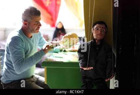 Januar 13, 2019 - Gaza, Gazastreifen, Palästinensische Autonomiegebiete - eine palästinensische Künstlerin, Mahdi Karira, 39, macht eine Marionette an seinem Haus, in Gaza Stadt, am 13. Januar 2019. Eine Marionette ist eine Marionette von oben über Kabel oder Streicher je nach regionalen Variationen gesteuert. Ein Marionettentheater Puppenspieler ist ein marionettist genannt. Marionetten sind mit der Puppenspielerin versteckt vor einem Publikum gezeigt, indem Sie eine vertikale oder horizontale Control Bar in verschiedenen Formen von Theater oder Unterhaltungsmöglichkeiten oder Betrieben. Sie haben auch in Film und Fernsehen eingesetzt. Die Befestigung der Saiten variiert ein Stockfoto