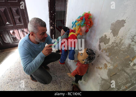 Januar 13, 2019 - Gaza, Gazastreifen, Palästinensische Autonomiegebiete - eine palästinensische Künstlerin, Mahdi Karira, 39, macht eine Marionette an seinem Haus, in Gaza Stadt, am 13. Januar 2019. Eine Marionette ist eine Marionette von oben über Kabel oder Streicher je nach regionalen Variationen gesteuert. Ein Marionettentheater Puppenspieler ist ein marionettist genannt. Marionetten sind mit der Puppenspielerin versteckt vor einem Publikum gezeigt, indem Sie eine vertikale oder horizontale Control Bar in verschiedenen Formen von Theater oder Unterhaltungsmöglichkeiten oder Betrieben. Sie haben auch in Film und Fernsehen eingesetzt. Die Befestigung der Saiten variiert ein Stockfoto