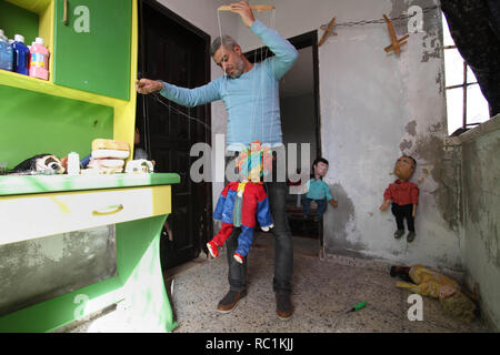 Januar 13, 2019 - Gaza, Gazastreifen, Palästinensische Autonomiegebiete - eine palästinensische Künstlerin, Mahdi Karira, 39, macht eine Marionette an seinem Haus, in Gaza Stadt, am 13. Januar 2019. Eine Marionette ist eine Marionette von oben über Kabel oder Streicher je nach regionalen Variationen gesteuert. Ein Marionettentheater Puppenspieler ist ein marionettist genannt. Marionetten sind mit der Puppenspielerin versteckt vor einem Publikum gezeigt, indem Sie eine vertikale oder horizontale Control Bar in verschiedenen Formen von Theater oder Unterhaltungsmöglichkeiten oder Betrieben. Sie haben auch in Film und Fernsehen eingesetzt. Die Befestigung der Saiten variiert ein Stockfoto