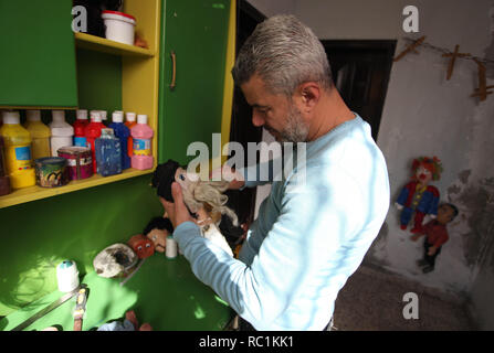 Januar 13, 2019 - Gaza, Gazastreifen, Palästinensische Autonomiegebiete - eine palästinensische Künstlerin, Mahdi Karira, 39, macht eine Marionette an seinem Haus, in Gaza Stadt, am 13. Januar 2019. Eine Marionette ist eine Marionette von oben über Kabel oder Streicher je nach regionalen Variationen gesteuert. Ein Marionettentheater Puppenspieler ist ein marionettist genannt. Marionetten sind mit der Puppenspielerin versteckt vor einem Publikum gezeigt, indem Sie eine vertikale oder horizontale Control Bar in verschiedenen Formen von Theater oder Unterhaltungsmöglichkeiten oder Betrieben. Sie haben auch in Film und Fernsehen eingesetzt. Die Befestigung der Saiten variiert ein Stockfoto