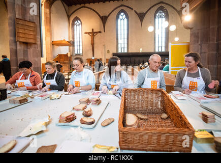 Stuttgart, Deutschland. 13 Jan, 2019. Freiwillige machen Brot während des ersten Tages des Vesper Kirche. Zum 25. Mal, die älteste Vesperkirche in Deutschland bietet bedürftigen Menschen mit warmen Mahlzeiten und mehr für sieben Wochen. Credit: Sebastian Gollnow/dpa/Alamy leben Nachrichten Stockfoto