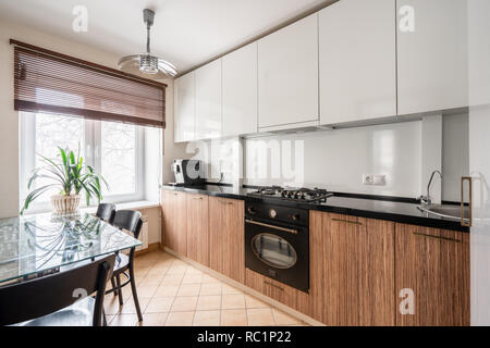 Russland, Nishnij Nowgorod - Januar 10, 2018: Private Wohnung. Interior Design. Kleine, moderne Küche in Weiß und WENGE Farben. Esstisch, Gas kochen Stockfoto