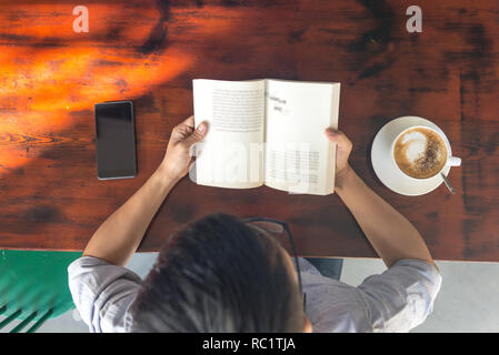 Hohe Betrachtungswinkel und der junge Mann lesen Buch Stockfoto