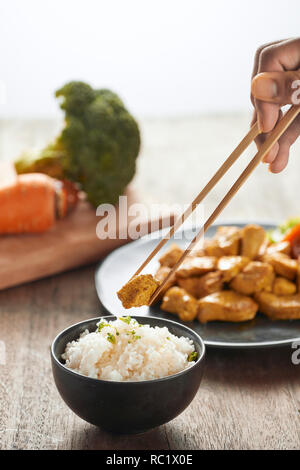 Weißer Reis mit Curry und Huhn in schwarz Platte auf hölzernen Tisch Stockfoto