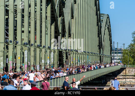 Menschen zu Fuß über die Hohenzollernbrücke in Köln, berühmt für Tausende von pad Schlösser von Liebhabern. Stockfoto