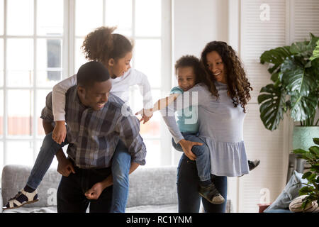 Afrikanische amerikanische Eltern huckepack Sohn und Tochter in Wohn Stockfoto