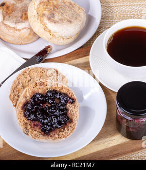 Ansicht eines englischen Muffin mit Blaubeer-marmelade auf einem Teller mit Tasse Kaffee Stockfoto