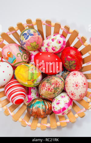 Bunt verziert und Ostereier in Holz- korb auf weißem Hintergrund gemalt. Ostern Konzept. Stockfoto