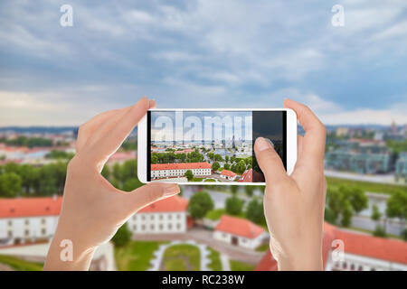 Ein Tourist macht ein Foto von Antenne Panoramablick auf die Hauptstadt von Litauen - Vilnius auf einem Mobiltelefon Stockfoto