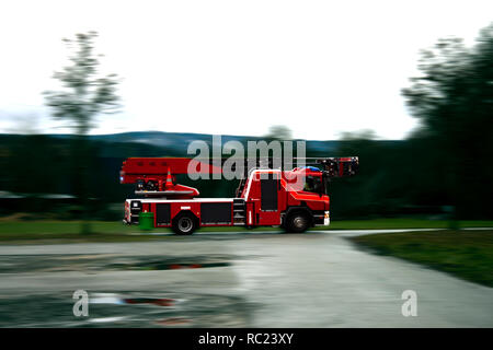 Feuerwehrmann Lkw mit Sirene und Blaulicht schnell über eine nasse Straße fahren. Stockfoto