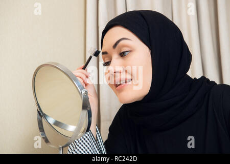 Eine junge muslimische Frau ihre Augenbrauen formen mit einer Bürste Stockfoto